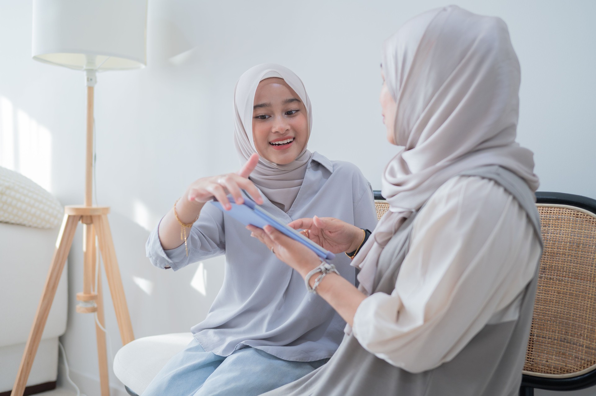 Asian Malay mother with daughter using smart tablet to search net eshopping for hari raya stock photo